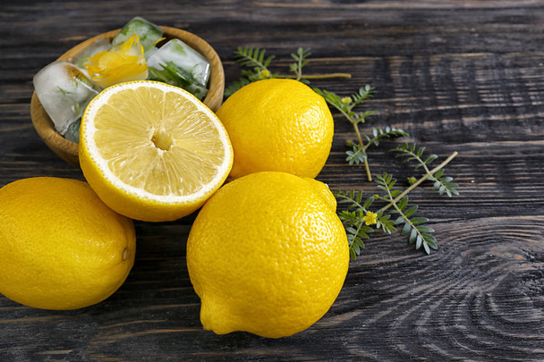 frische reife Zitronen mit Eiswürfeln auf Holzgrund - Foto, Bild