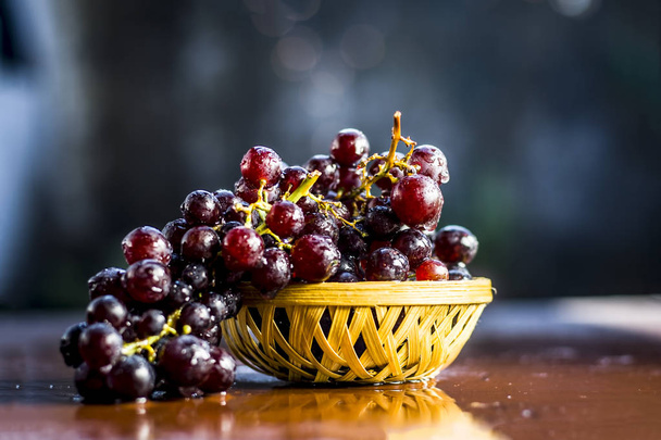 Close up view of Grapes in wicker basket on wooden surface - Foto, imagen