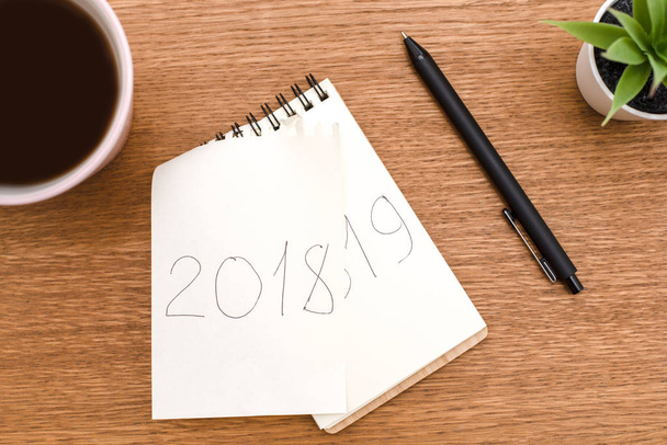 Koffie en notebook waar u doorgehaald de inscriptie 2018 en schriftelijke 2019 - Foto, afbeelding