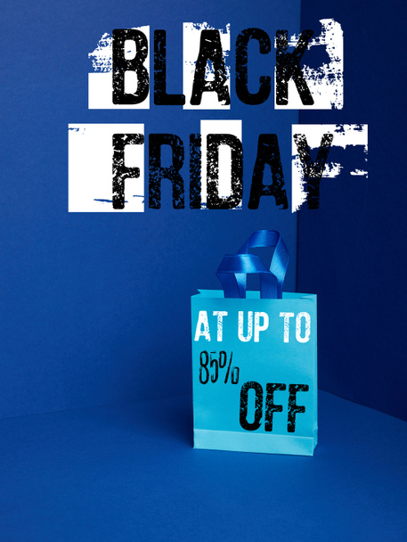 close up view of paper shopping bag on blue with black friday and 85 percents off discount - Fotografie, Obrázek