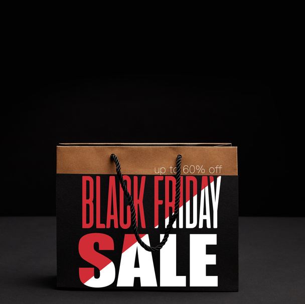 close up view of paper shopping bag on black backdrop with black friday sale and 60 percents discount - Фото, зображення