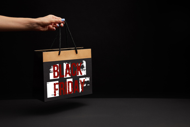 partial view of woman holding black shopping bag with black friday sale - Photo, Image