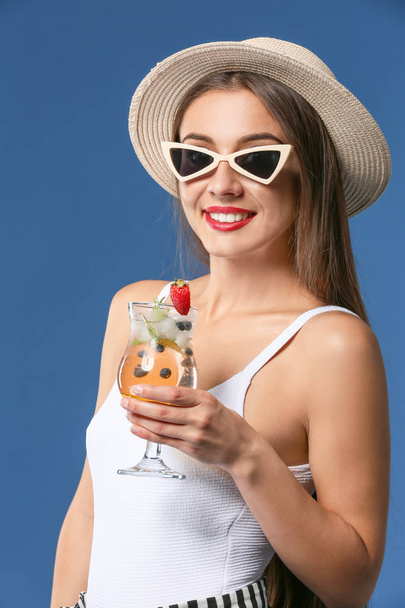 Beautiful woman with tasty summer cocktail on color background - Photo, Image