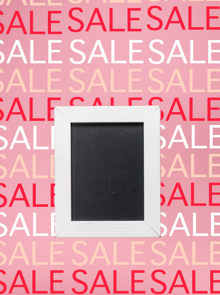 empty blackboard in white frame on pink background with sale signs - Фото, изображение
