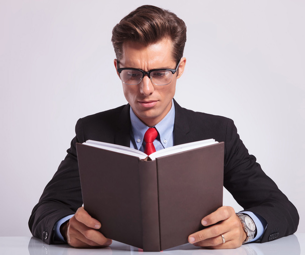 Business man lezing boek achter zijn Bureau - Foto, afbeelding