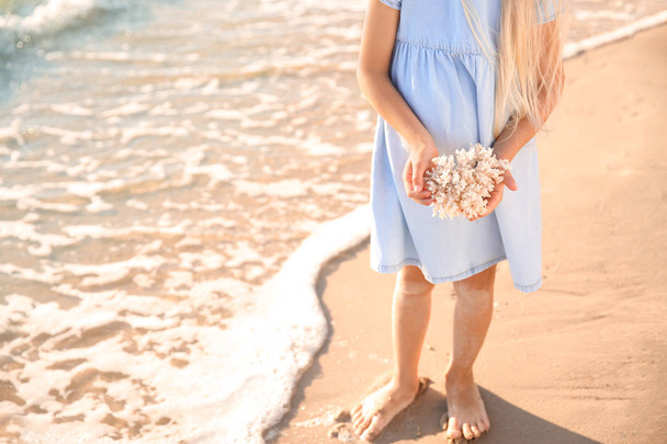Menina bonito com coral na praia do mar
 - Foto, Imagem