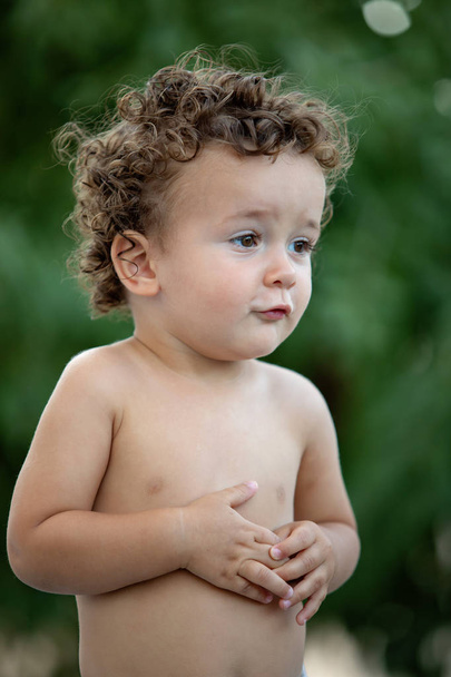 Beautiful baby with curly hair in the garden without t-shirt - Photo, Image