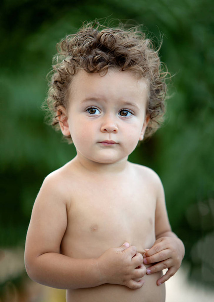 Bellissimo bambino con i capelli ricci in giardino senza t-shirt
 - Foto, immagini
