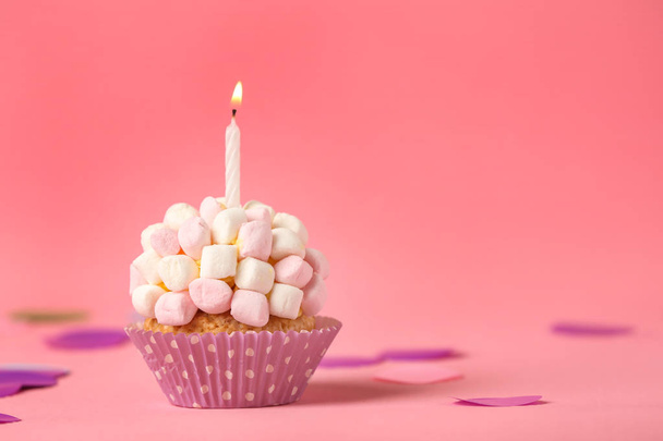 Delicious birthday cupcake with burning candle and marshmallows on color background - Фото, изображение