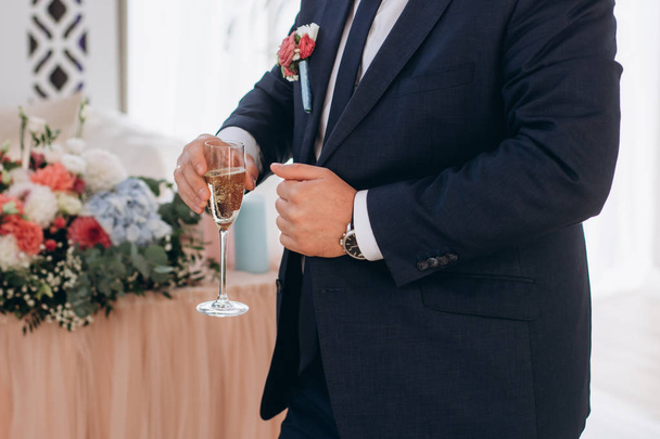 sposo in un abito blu tiene un bicchiere di champagne
 - Foto, immagini