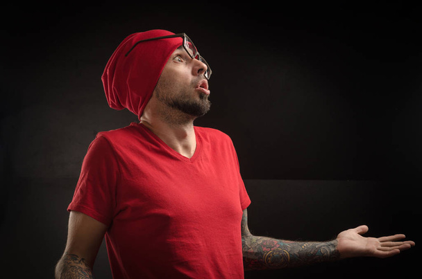 άντρας σε ένα κόκκινο καπέλο και t-shirt θέτοντας σε μαύρο φόντο - Φωτογραφία, εικόνα