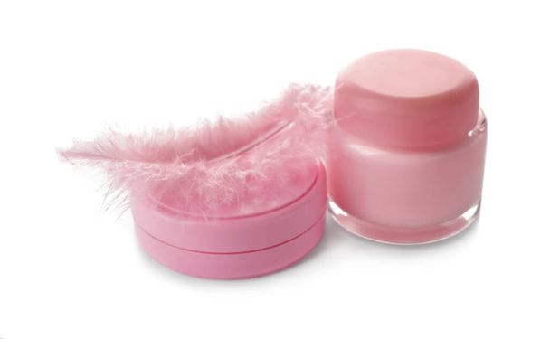 Frascos con crema corporal y pluma rosa sobre fondo blanco
 - Foto, imagen