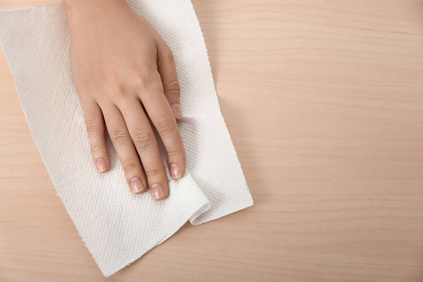 Woman wiping wooden table with paper towel - Foto, afbeelding