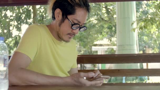 Slow motion 4 k of Casual asian man using smartphone . He is checking mails, chats or the news online. - Materiaali, video