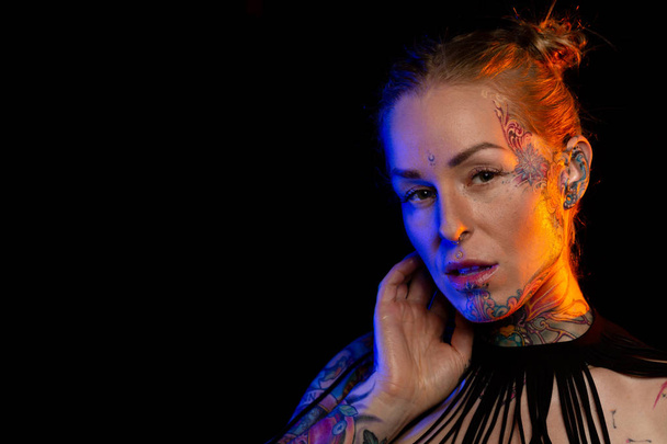 Umięśnione kaukaski kobieta z tatuażami i naoliwione skóry noszenia naszyjnik i kabaretki pozach bielizny pod kolorowe światła - Zdjęcie, obraz