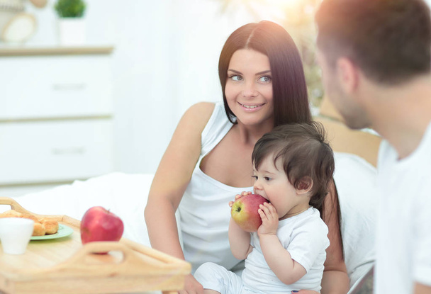 Family with little baby having breakfast in the bed. - 写真・画像