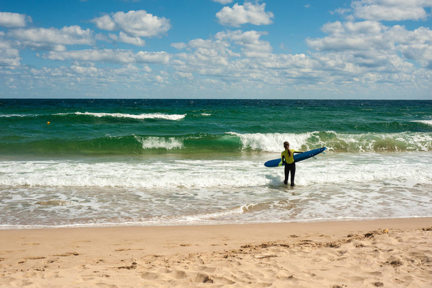 A menina aprende a andar de prancha no mar no verão. Montando em uma prancha de surf nas ondas em um lugar bonito. Escola de Surfista na praia
. - Foto, Imagem