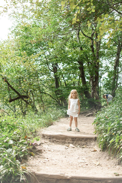 little girl in white dress walking in park - Photo, Image