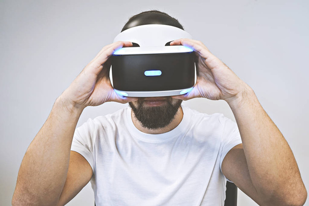 Бородатый человек использует 3D очки и наслаждается виртуальной реальностью на белом фоне
 - Фото, изображение