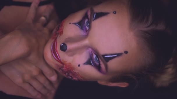 Zbliżenie twarzy kobiety z creepy Halloween makijaż pajac patrząc w kamerę. Twórczej, artystycznej, koncepcja Halloween - wideo w zwolnionym tempie - Materiał filmowy, wideo