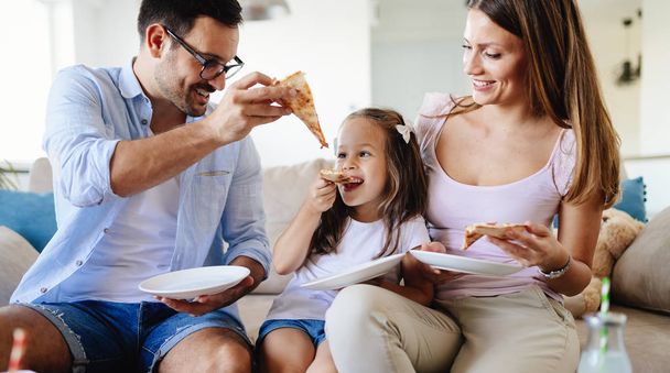 Happy smiling family sharing pizza together at home - Fotoğraf, Görsel