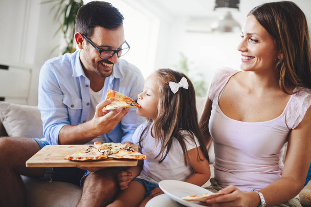 Happy smiling family sharing pizza together at home - 写真・画像