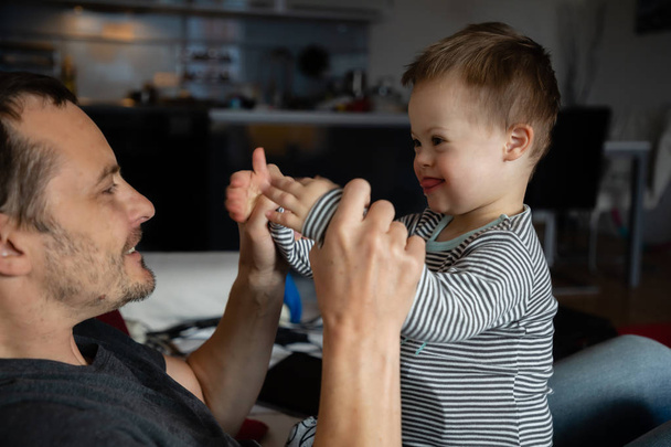 Cute boy with Down syndrome playing with dad on in home - Photo, Image