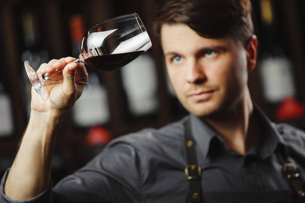 Bokal de vinho tinto no fundo, sommelier masculino apreciando bebida - Foto, Imagem