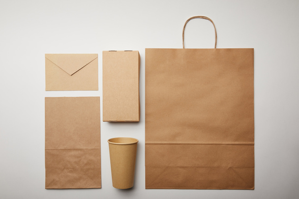 couche plate avec enveloppe, tasse en papier, sac de livraison de nourriture en papier sur surface blanche, concept minimaliste
  - Photo, image