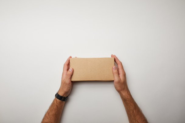 imagen recortada del hombre sosteniendo la caja de comida de entrega en la superficie blanca
  - Foto, Imagen