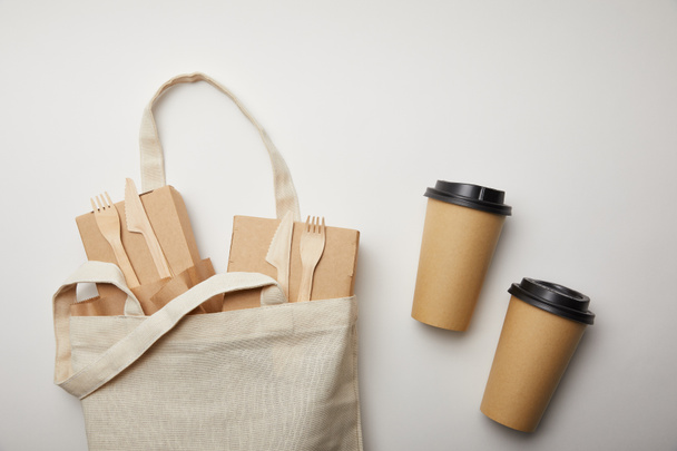 vue surélevée du sac en coton avec des boîtes à nourriture et deux tasses à café jetables sur la surface blanche
 - Photo, image