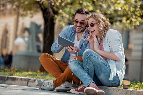 pareja joven usando la tableta y escuchando música en la calle
 - Foto, Imagen
