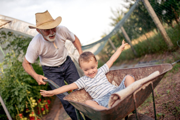 happy Grandfather with grandson enjoying working together in garden - Photo, Image