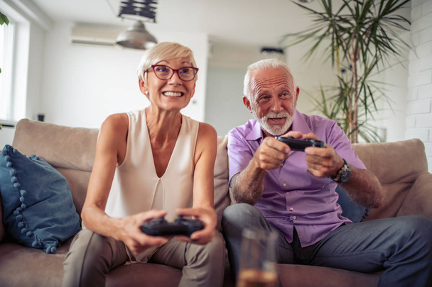 heureux couple de personnes âgées avoir beaucoup de temps et de jouer ensemble à un jeu vidéo à la maison
 - Photo, image