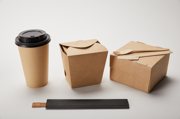 vue rapprochée de tasse à café en papier, boîtes à nourriture et baguettes sur blanc
  - Photo, image