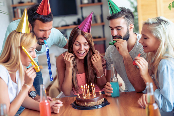 Счастливые друзья отмечают день рождения праздничным тортом
. - Фото, изображение