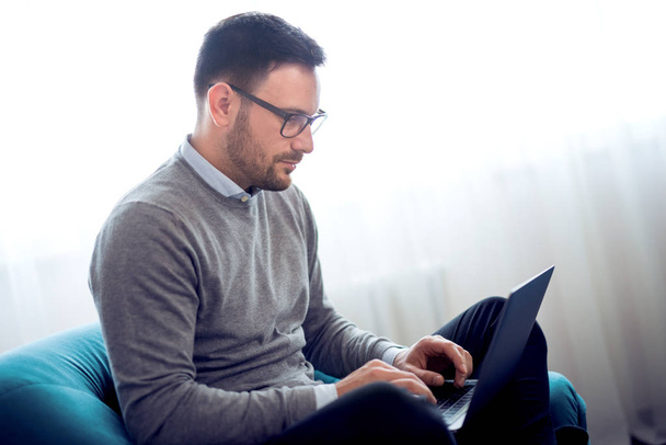 Fiatal ember dolgozik a laptop a fotel otthon office. - Fotó, kép
