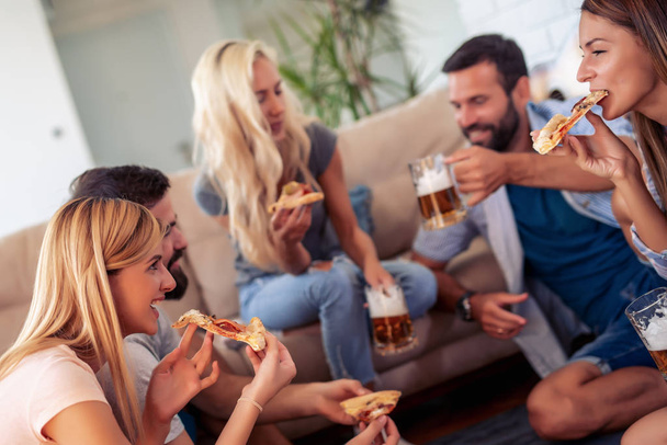 Allegro gruppo di amici che si divertono a casa, mangiano pizza
. - Foto, immagini