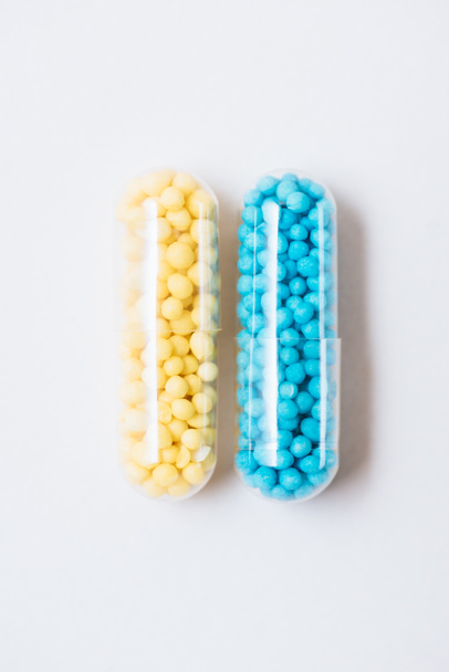 top view of blue and yellow medical capsules on white - Фото, зображення