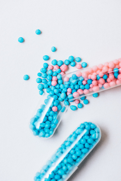 Close-up shot van gebroken blauwe en roze medische capsules op witte ondergrond - Foto, afbeelding