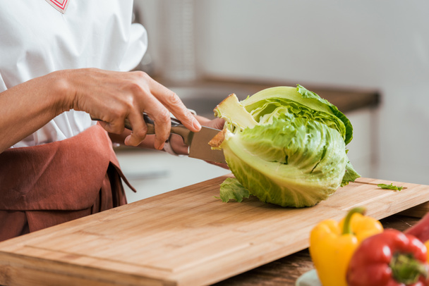 abgeschnittenes Bild einer Frau, die zu Hause Salat zubereitet und Kohl schneidet - Foto, Bild