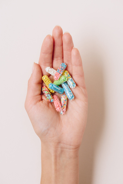 bijgesneden schot van vrouw met verschillende kleurrijke medische capsules op wit - Foto, afbeelding