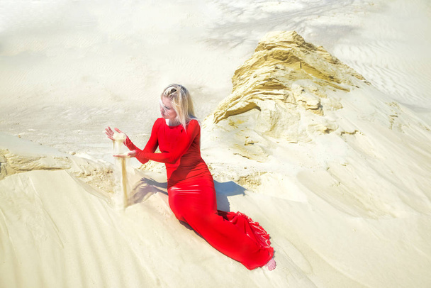 ξανθιά γυναίκα που ποζάρει στο κόκκινο φόρεμα στην έρημο  - Φωτογραφία, εικόνα