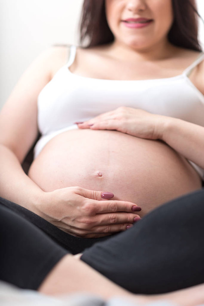 беременная женщина держит руки на животе - Фото, изображение