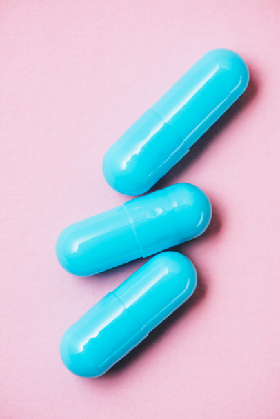 Close-up shot van blauwe medische capsules op roze - Foto, afbeelding