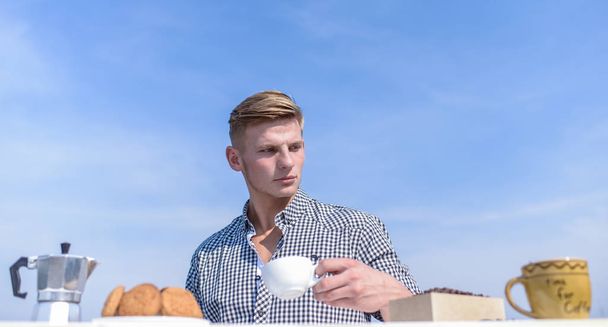 Daily traditions. Breakfast outdoors weekend tradition. Guy enjoy great beginning of day. Man hold cup of coffee sky background. Man muscular athlete drink morning coffee. Pleasant morning outdoors - Foto, afbeelding