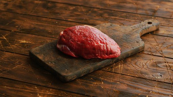 Big fresh piece of meat laid on wooden cutting board - Фото, зображення