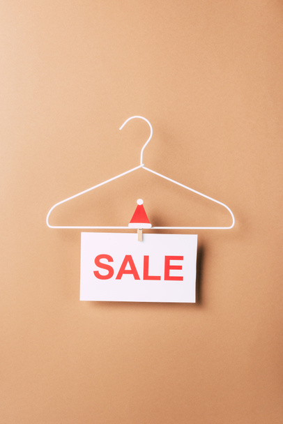 Kleiderbügel mit Verkaufsschild für Weihnachtseinkäufe auf beige - Foto, Bild