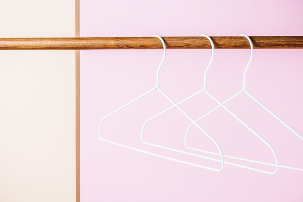 three white empty hangers for shopping on pink - Foto, Imagen