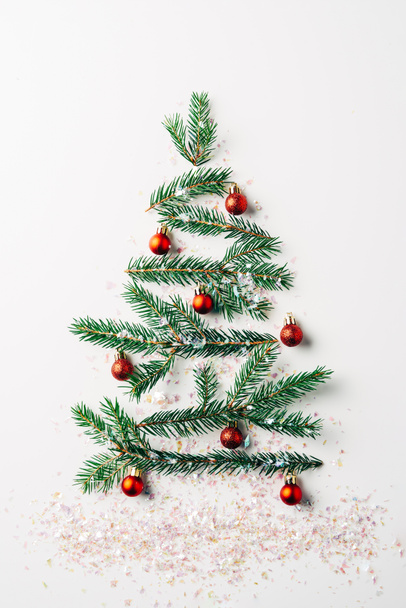 top view of green pine branch decorated as festive christmas tree with glitters on white background - Photo, Image